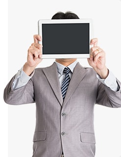 Мужчина в строгом костюме закрывает лицо планшетом с выключенным черным экраном