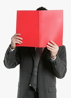 Мужчина в строгом костюме закрывает лицо раскрытой красной папкой